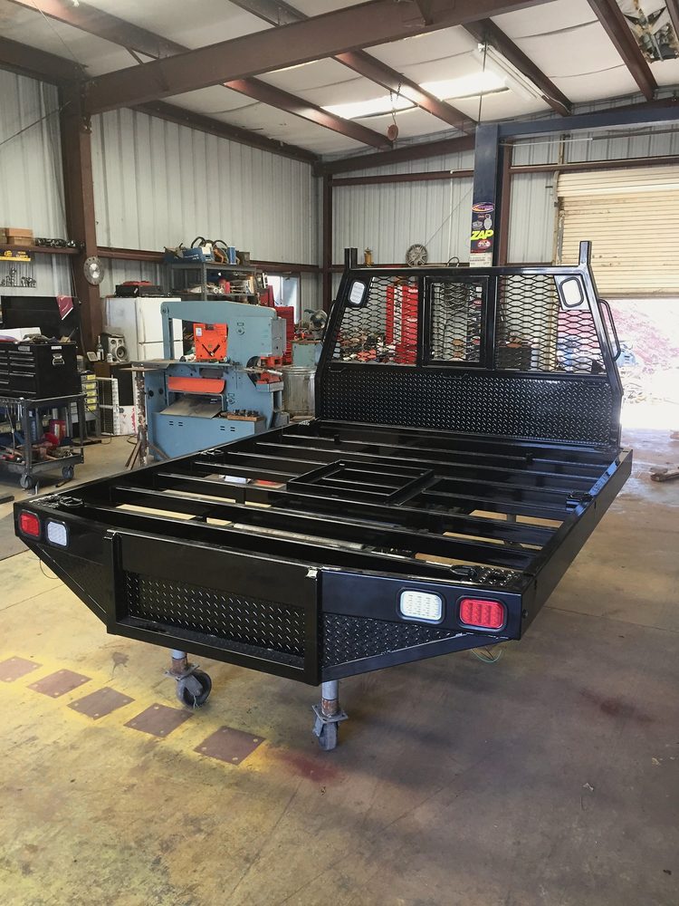 Black steel flatbed truck body with headache rack in our shop