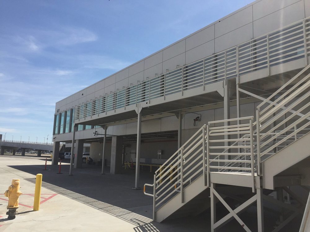 Metal stair and horizontal bar guardrail along a second floor walkway