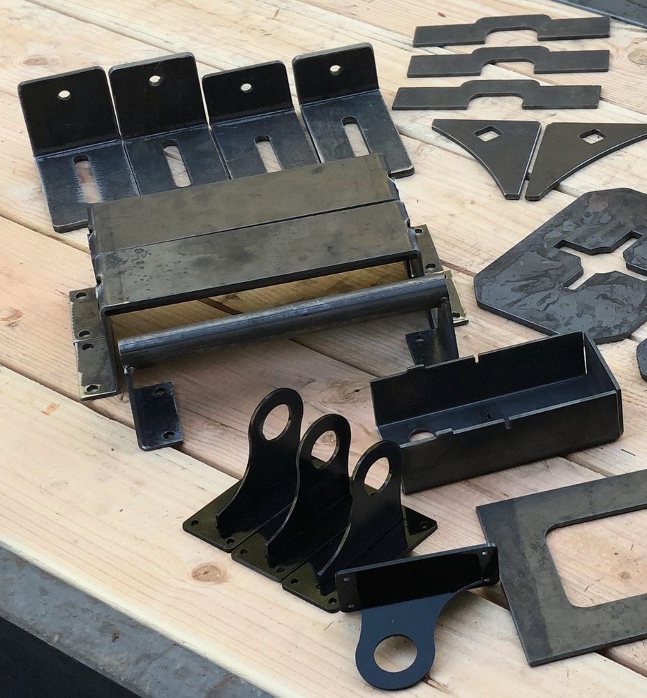 Laser-cut and formed steel parts: hinge brackets, a roller frame, a tray and slotted brackets
